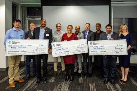 Winners of the Market Pulse Pitch standing with checks