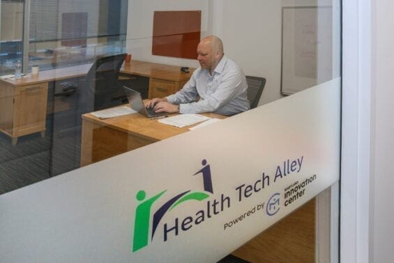 A man is seen working at his desk through the glass door of his office.