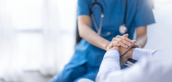 Closeup of a nurse holding the hand of a patient.