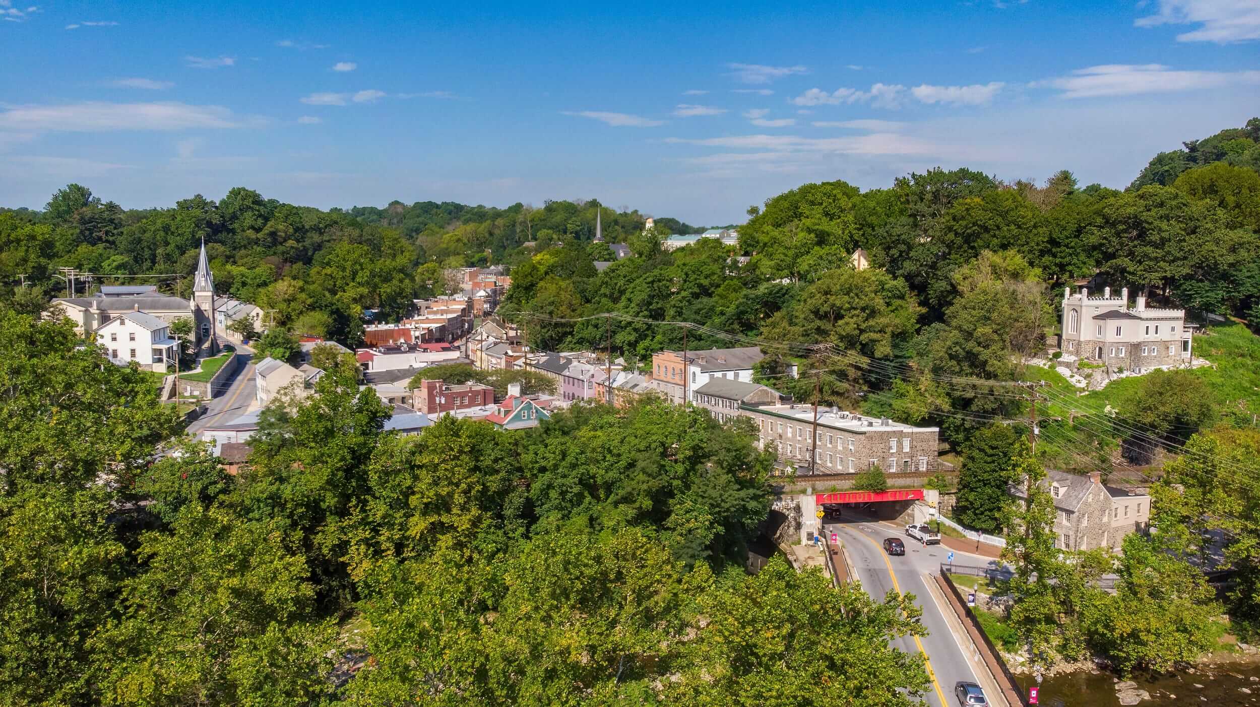 An aerial shot of treetops and quaint buildings in a wooded downtown area.